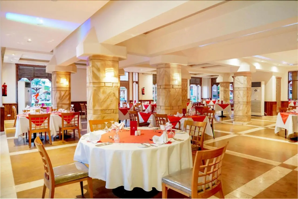 Charmillion Club Aqua Park: A spacious dining room with neatly set tables, wooden chairs, and a food display counter.