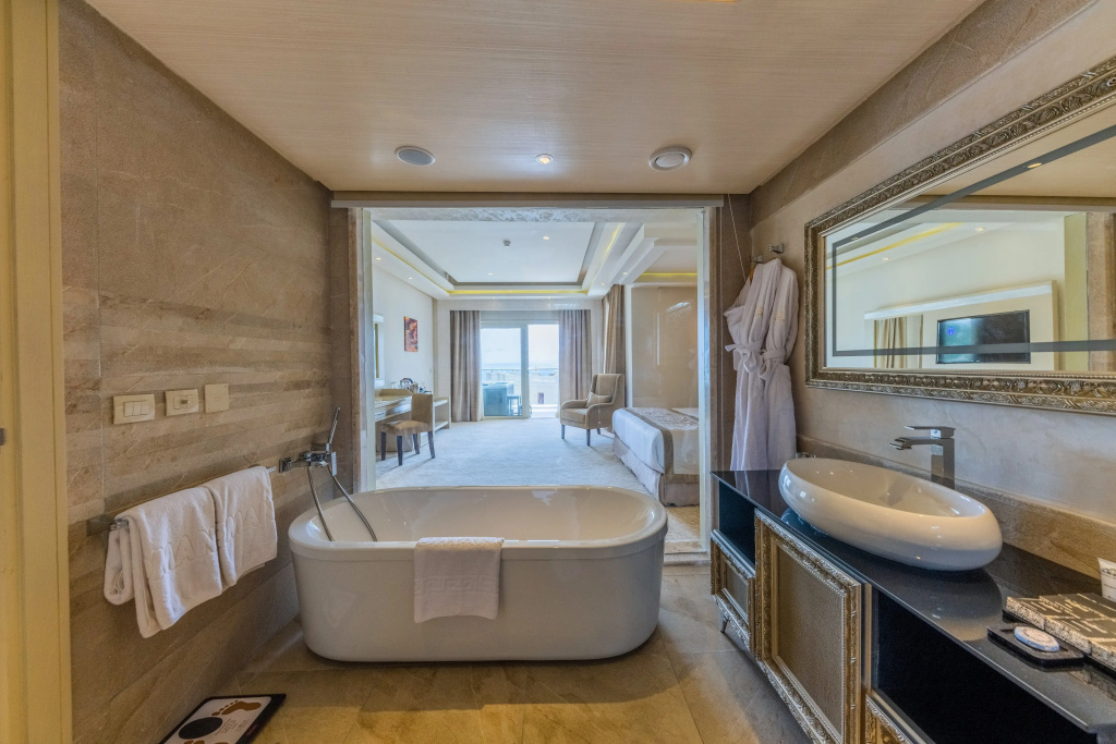 KaiSol Romance Resort Sahl Hasheesh (Adults Only): A spacious bathroom with a freestanding bathtub, vessel sink, and a view into the adjoining bedroom.