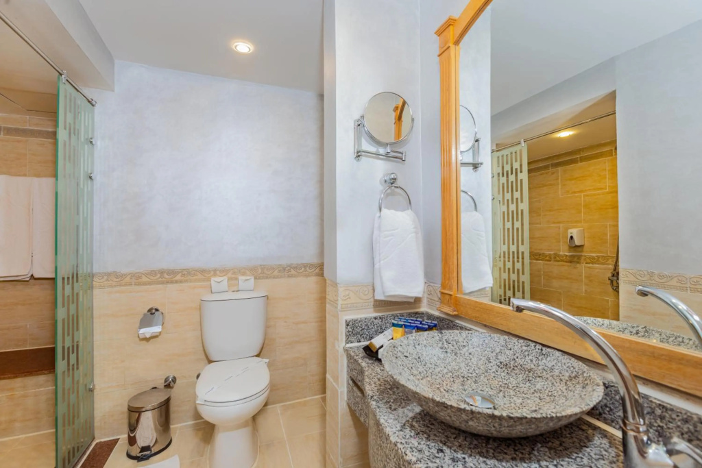 Pickalbatros Jungle Aqua Park - Neverland Hurghada: Bathroom with a vessel sink, large mirror, toilet, and tiled finishes.