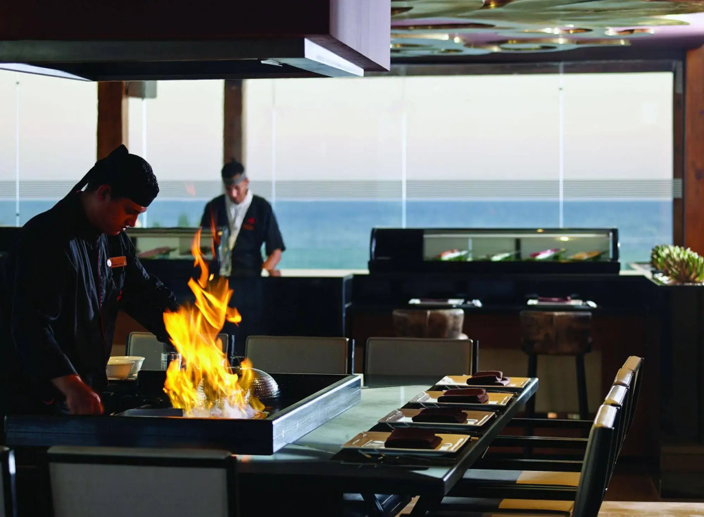 Coral Sea Sensatori Resort: Chefs prepare food over an open flame at a counter-service dining area.