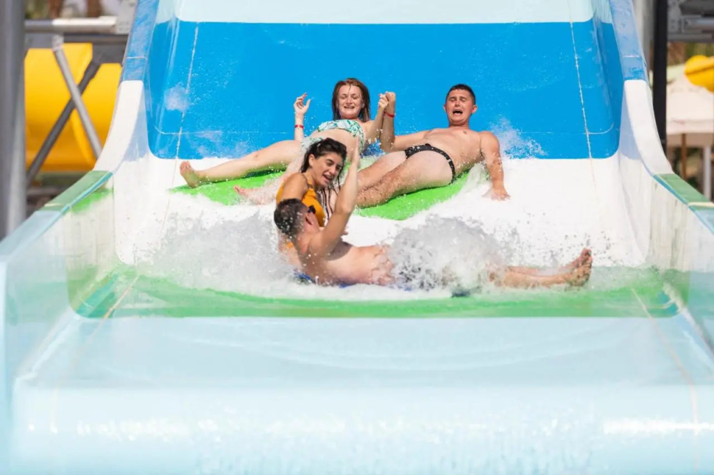 Xperience Kiroseiz Parkland Resort: Guests ride an inflatable raft down a water slide into a splash pool.