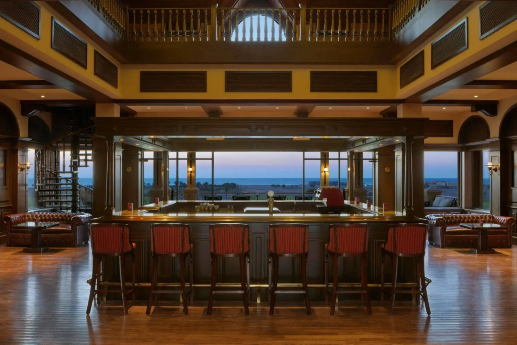 The Cascades Golf Resort Spa and Thalasso: A spacious wood-paneled bar with counter seating, lounge chairs, and expansive coastal views.