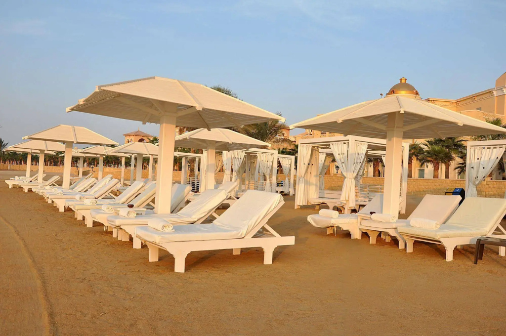 KaiSol Romance Resort Sahl Hasheesh (Adults Only): Relax on cushioned loungers beneath large umbrellas, with curtained cabanas nearby.