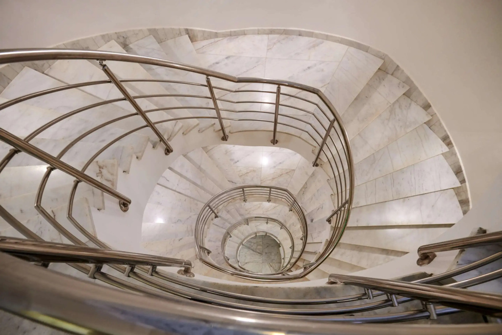 Steigenberger Pure Lifestyle (Adults Only): A dramatic spiral staircase with pale stone steps and curved metal railings.