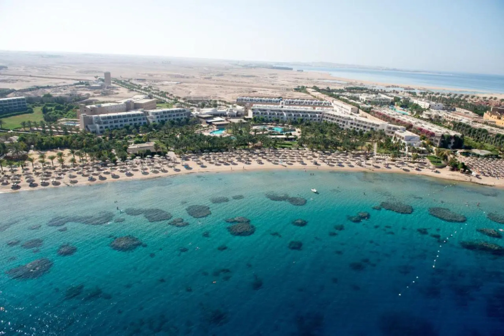Fort Arabesque Resort, Spa & Villas: A beachfront resort with turquoise pools, rows of shaded beach loungers, and clear water along the sandy shore.