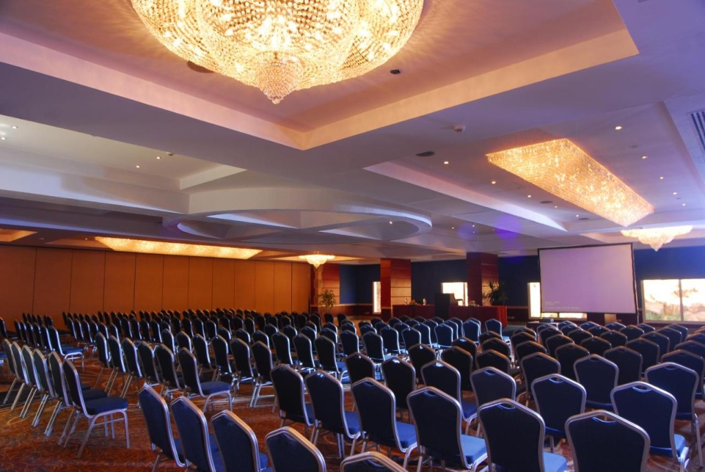 Naama Bay Hotel & Resort: A spacious conference room with rows of chairs, a large presentation screen, and decorative chandeliers.