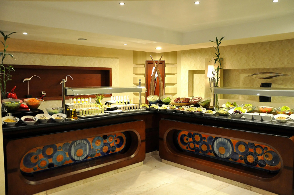 KaiSol Romance Resort Sahl Hasheesh (Adults Only): An indoor buffet counter displays salads, condiments, and other prepared foods.