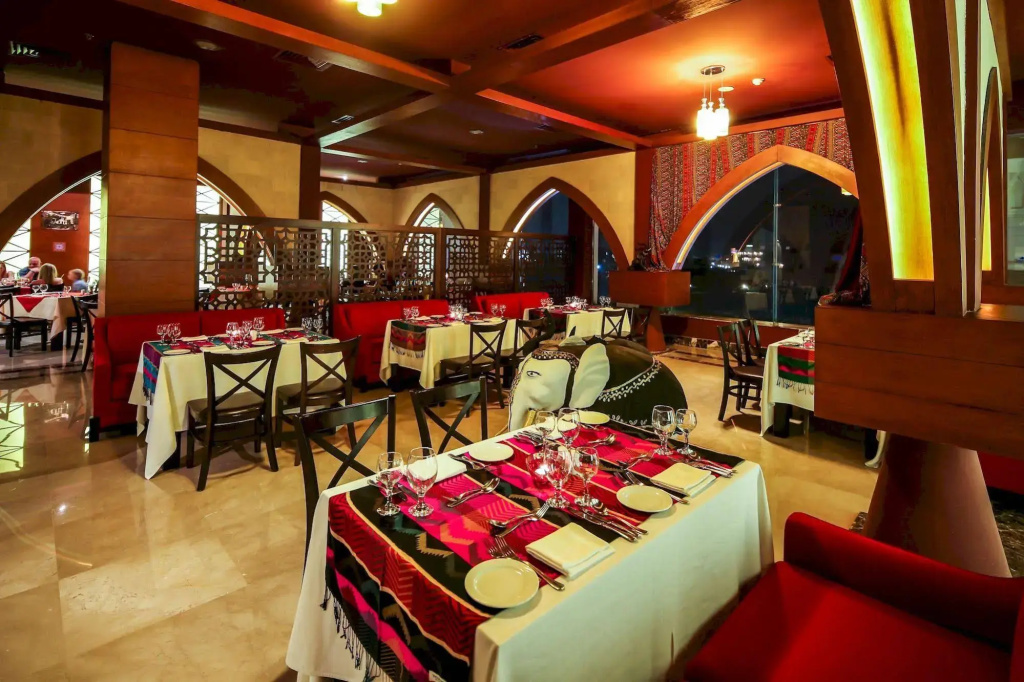 Jasmine Palace Resort & Spa: A warmly lit restaurant dining room with tables set for service and comfortable banquette seating.