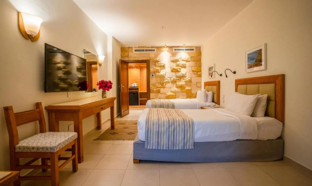 Fort Arabesque Resort, Spa & Villas: A warm-toned guest room with two separate beds, a wall-mounted TV, and a writing desk.