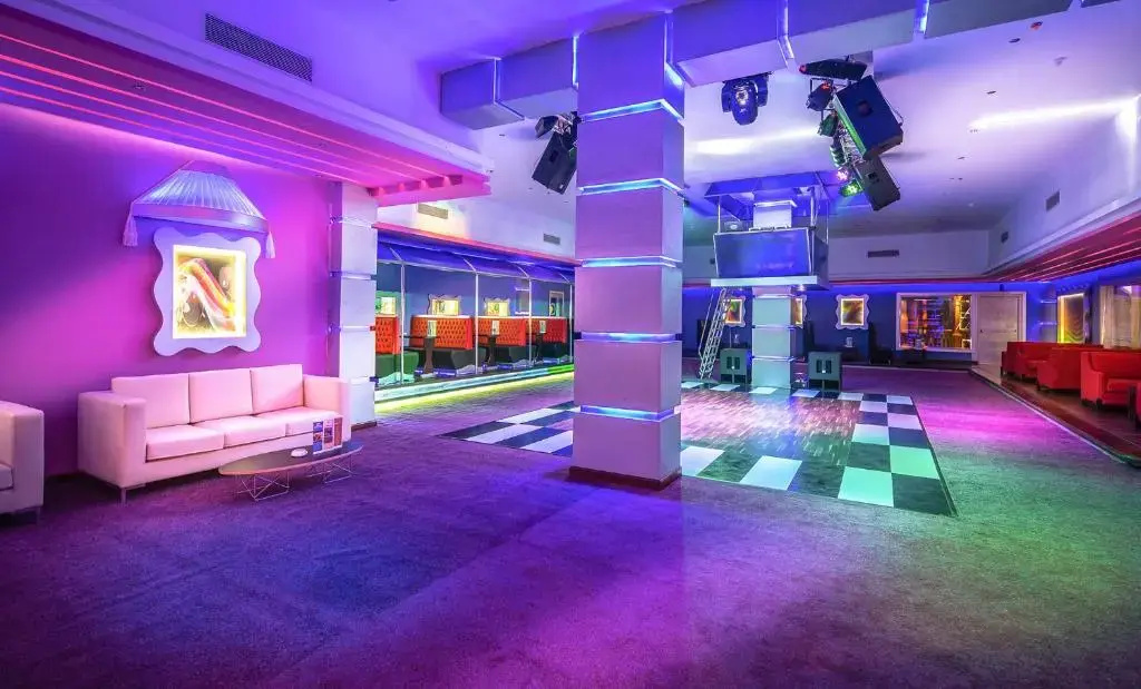 Jasmine Palace Resort & Spa: A vibrant indoor entertainment lounge with a checkerboard dance floor, comfortable seating, and colorful club lighting.