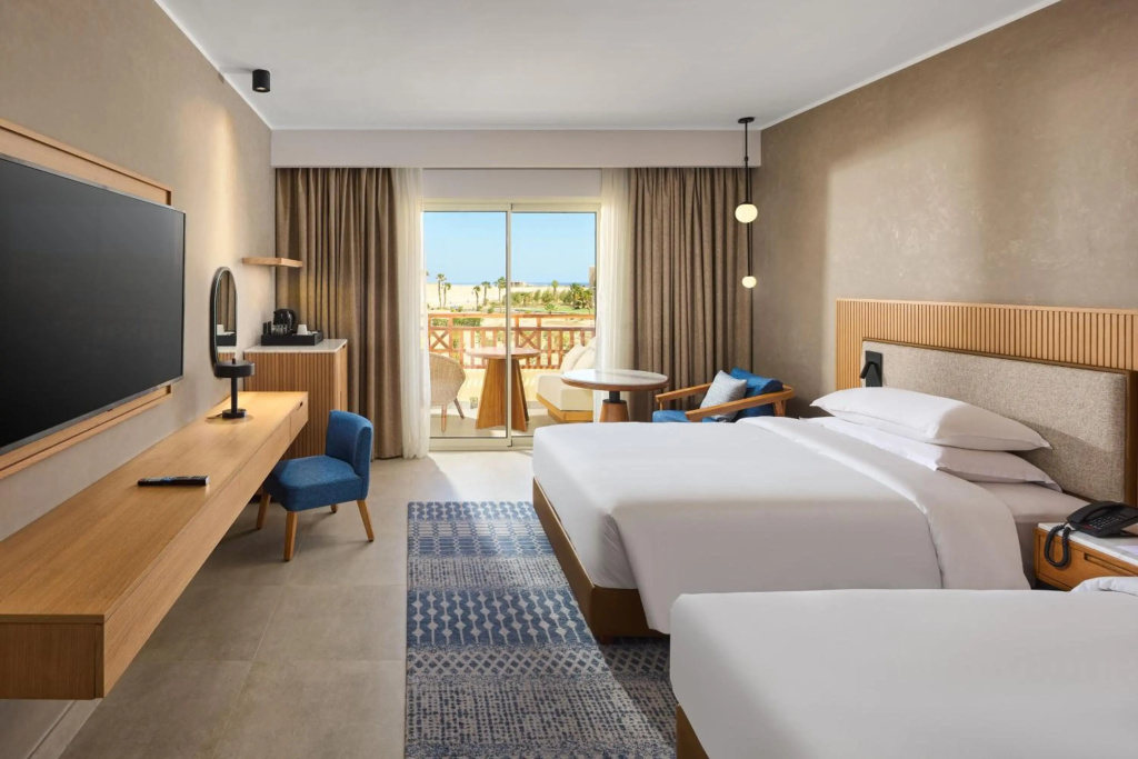 Sheraton Soma Bay Resort: Bright guest room with two beds, a sitting area, and glass doors opening to a balcony.