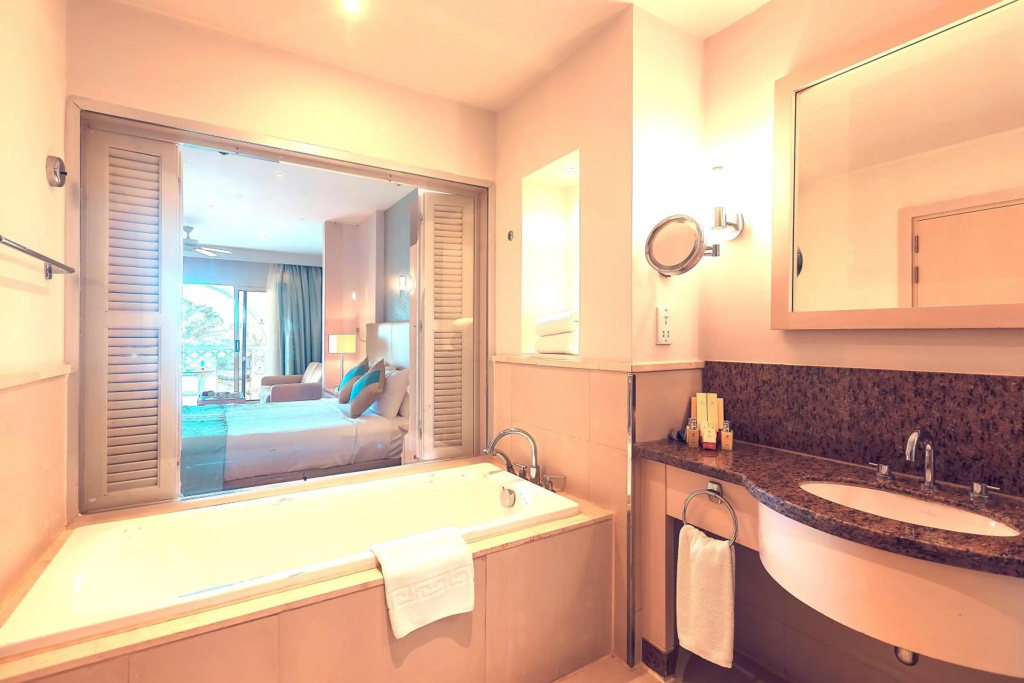 Old Palace Sahl Hasheseh: A bright bathroom with a large bathtub, single-sink vanity, and a view into the bedroom.
