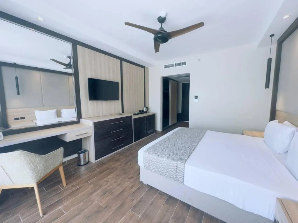 Panorama Naama Heights Sharm El Sheikh: Bright hotel bedroom with a large bed, wall-mounted TV, and a desk area.