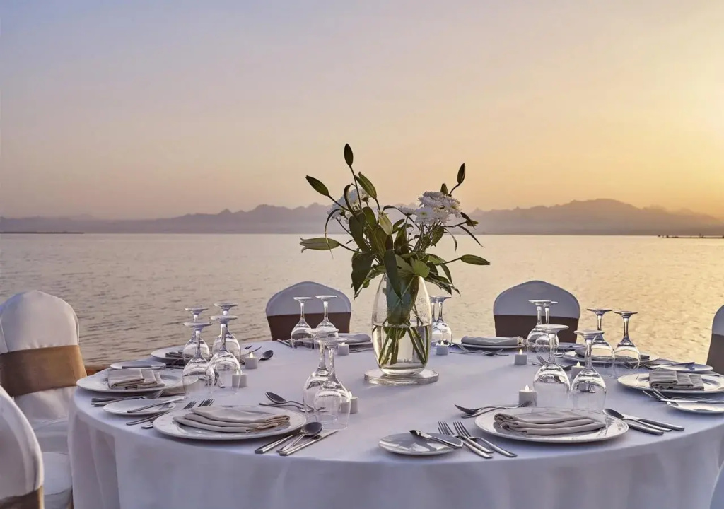 Sheraton Soma Bay Resort: An elegant outdoor dining table set beside the water at sunset.