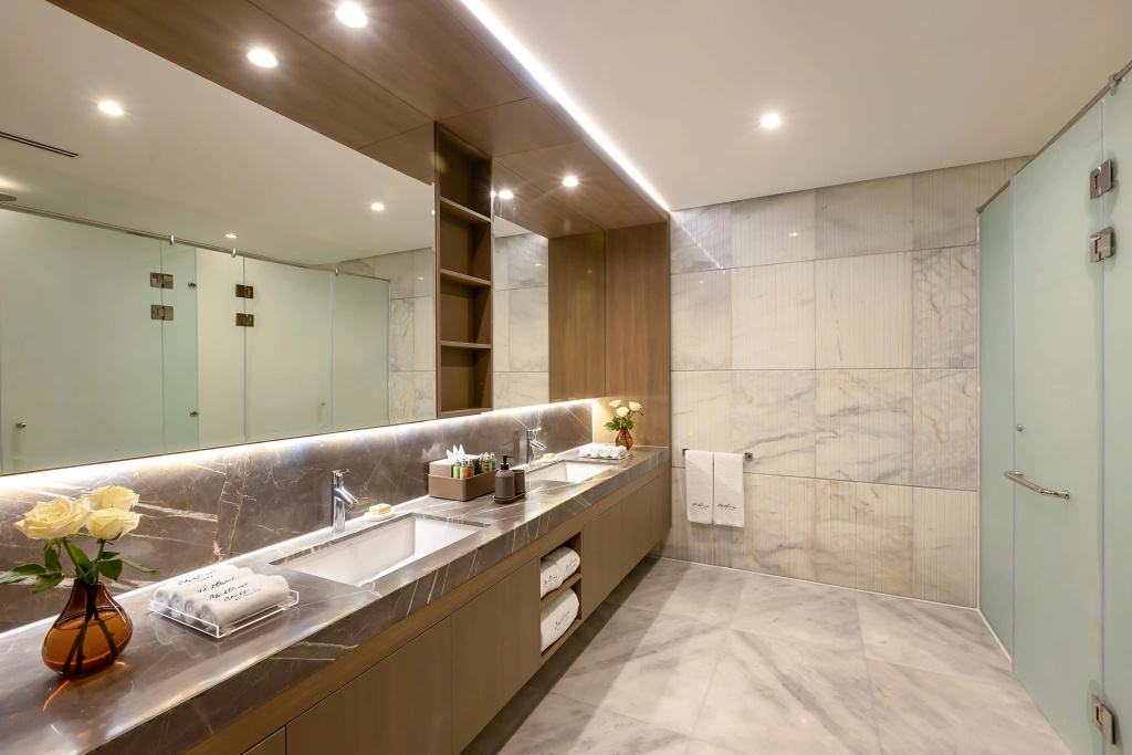 Club Prive By Rixos Sharm El Sheikh: A bright marble bathroom with a double vanity, large mirrors, and a glass-enclosed shower.