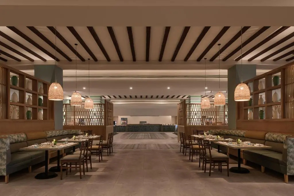 JAZ Elite Asteria Hotel: A spacious restaurant dining room with booth seating, set tables, and warm pendant lighting.