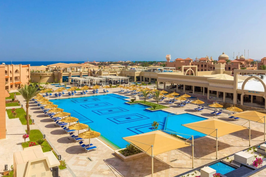 Pickalbatros Aqua Vista Resort - Hurghada: A spacious outdoor pool is surrounded by sun loungers, parasols, and shaded seating areas.