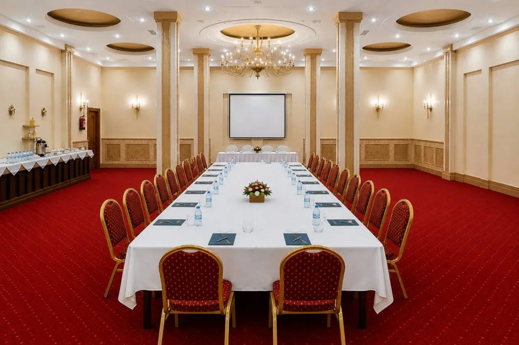 Royal Regency Club - Ultra All Inclusive: A formal meeting room with a long, fully set table, upholstered chairs, and a presentation screen.