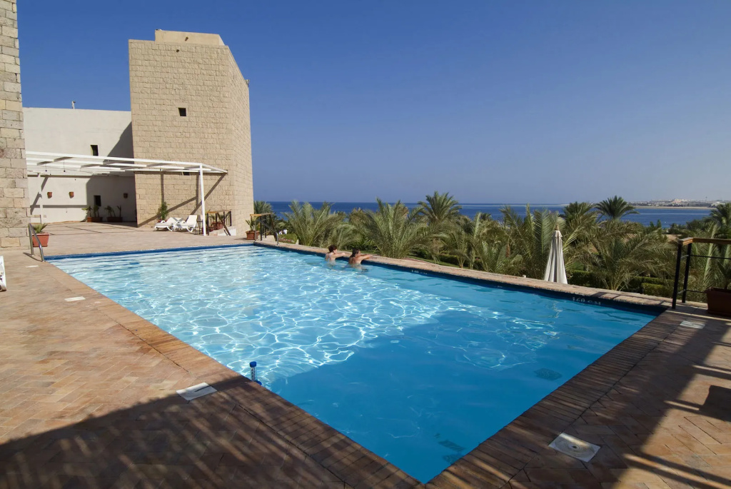 Fort Arabesque Resort, Spa & Villas: An outdoor pool with deck seating and views toward the sea and palm trees.
