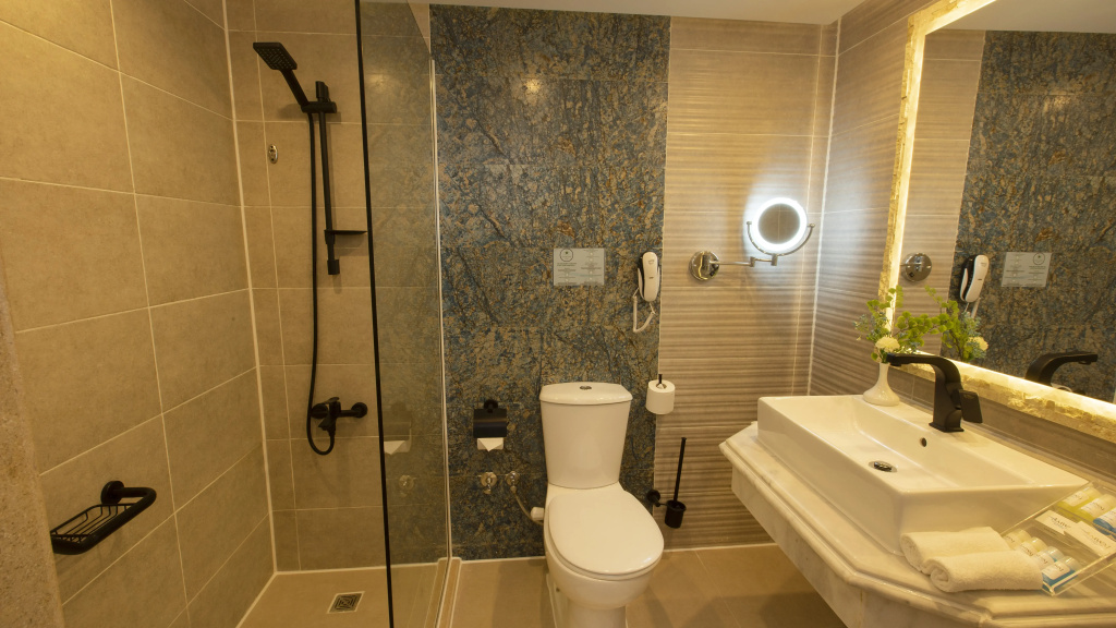 صورة: Amwaj Oyoun Resort & Casino Resort: A modern bathroom with a glass-enclosed shower, toilet, and illuminated vanity mirror.
