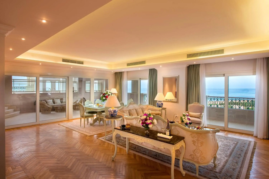 Baron Palace Sahl Hasheesh Resort: Elegant suite living and dining area with a balcony overlooking the sea.