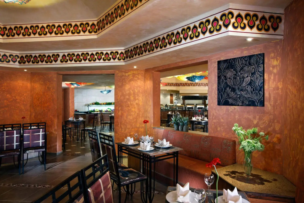 Pickalbatros Aqua Vista Resort - Hurghada: An ornate indoor dining room with set tables, dark chairs, and a service counter in the background.