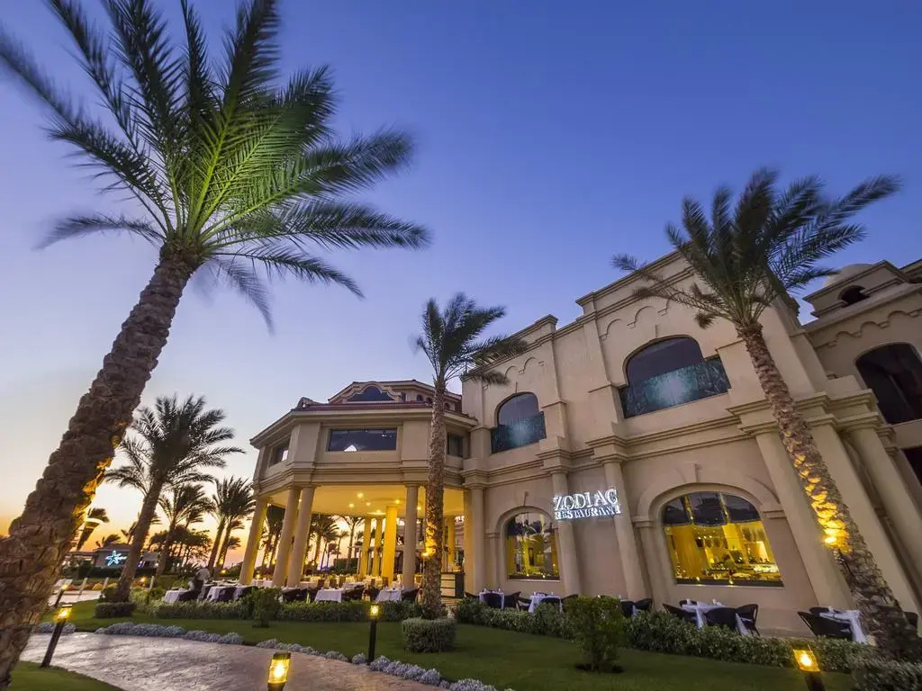 Rixos Sharm El Sheikh Ultra All Inclusive - Adults Friendly: The hotel’s Zodiac Restaurant has outdoor seating beneath palm trees beside a landscaped garden.