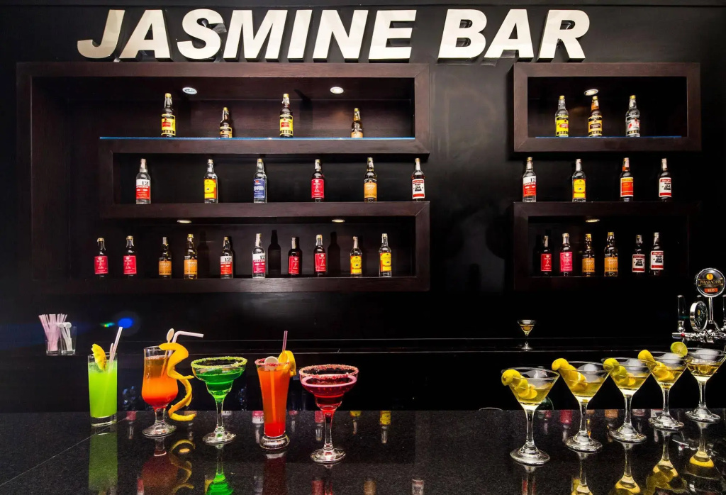 Jasmine Palace Resort & Spa: The Jasmine Bar features a polished counter, assorted spirits, and colorful cocktails.