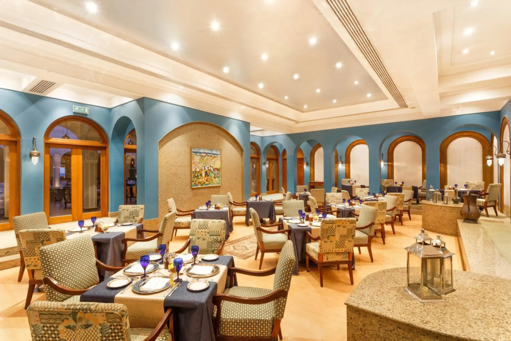 صورة: The Oberoi Beach Resort, Sahl Hasheesh: An elegant dining room with neatly set tables, patterned chairs, and tall arched windows.
