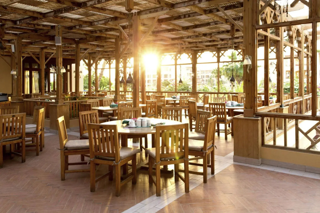 Robinson Soma Bay: A spacious dining room with wooden tables and chairs, large windows, and abundant natural light.