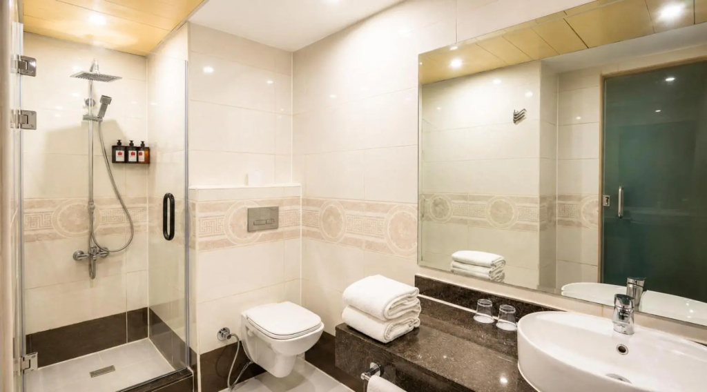 Romance Regency Club Adult Only (+16) - Ultra All Inclusive: A bright tiled bathroom with a glass-enclosed shower, bathtub, sink, and neatly folded towels.