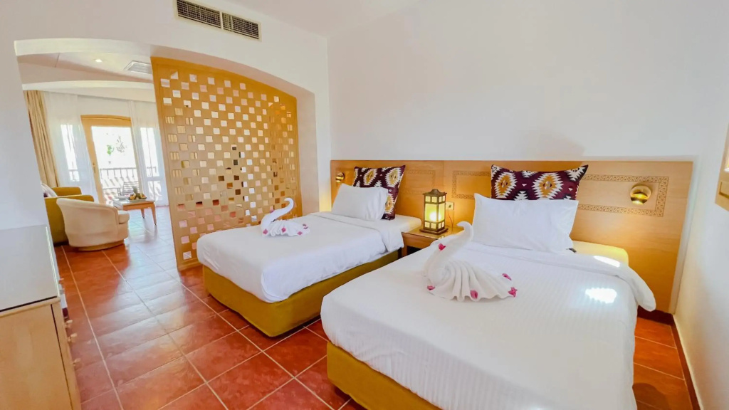 Tamra Beach Resort: A bright guest room with two twin beds, bedside lighting, and a small seating area by the window.