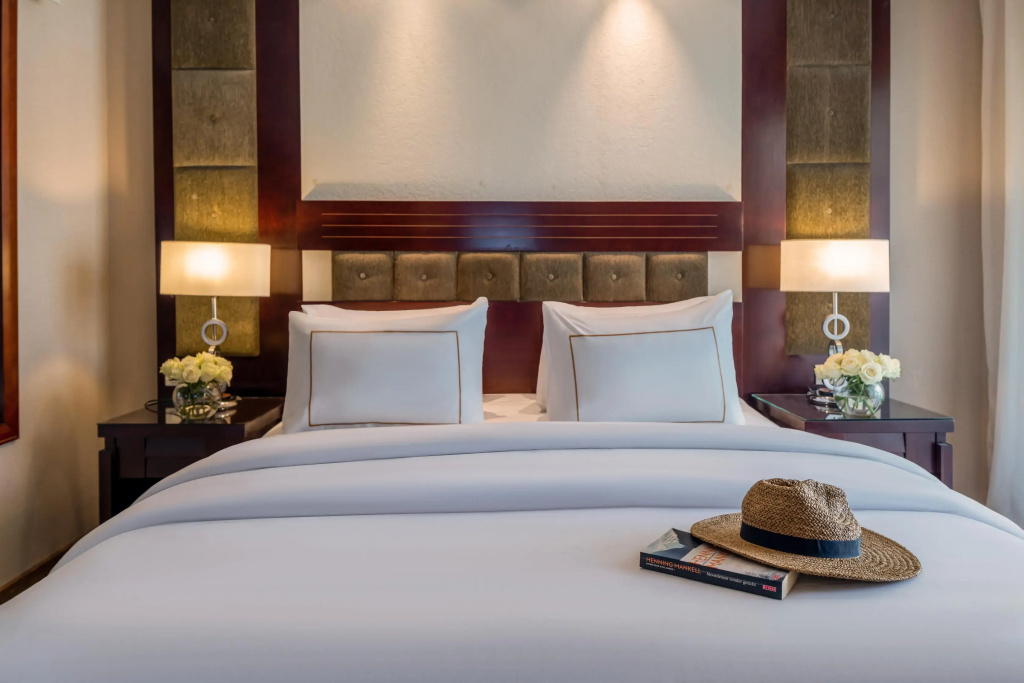 Rixos Sharm El Sheikh Ultra All Inclusive - Adults Friendly: A neatly made bed with a padded headboard, matching bedside lamps, and floral accents.