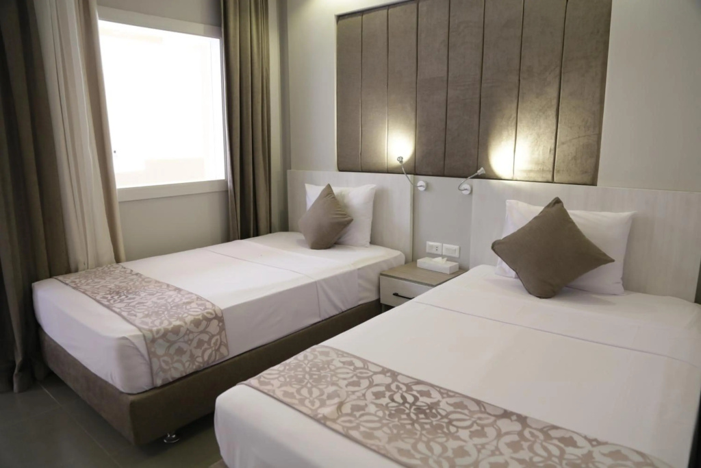 Aladdin Beach Resort - Families and Couples Only: Bright guest room with two separate beds, patterned runners, and bedside lighting.