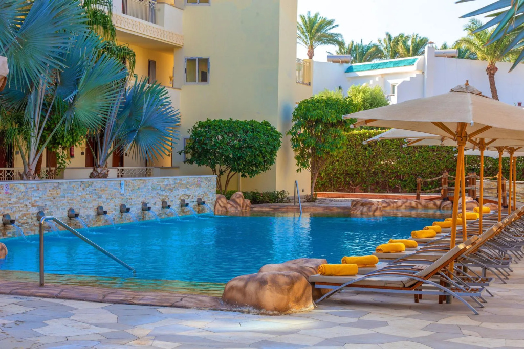 Xperience Sea Breeze Resort: Relax by the outdoor pool on a sun lounger beneath a shaded umbrella.