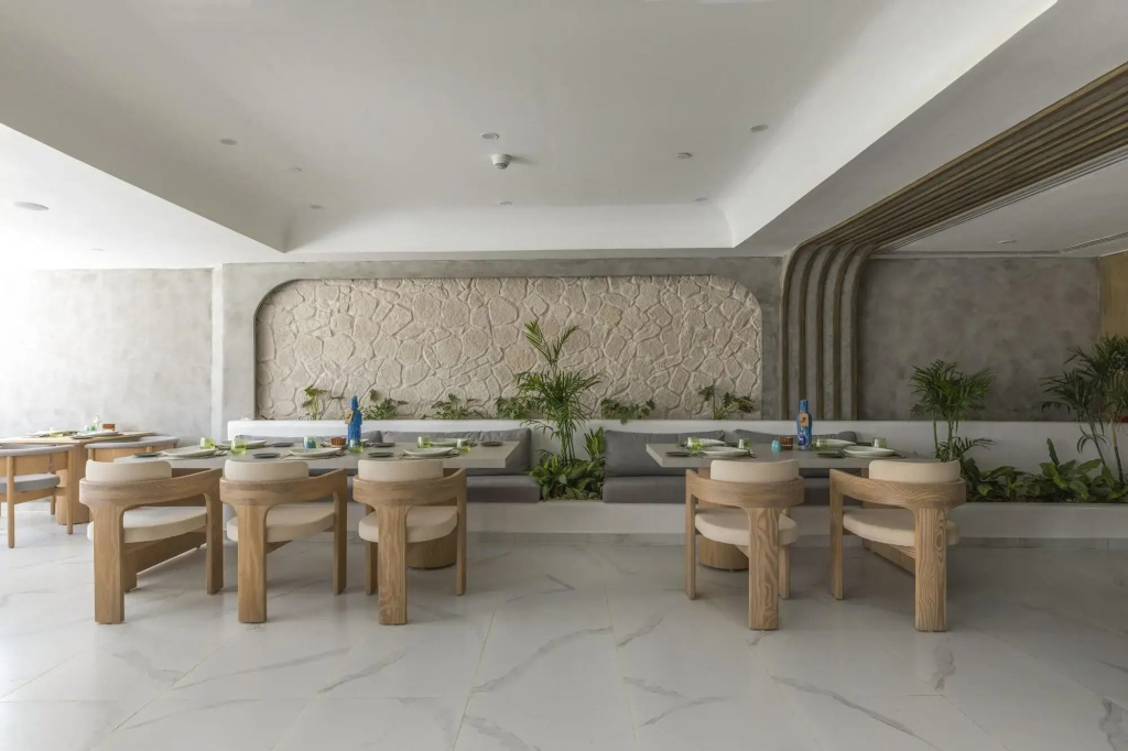 Meraki Resort Sharm El Sheikh: A bright, modern dining room with set tables, cushioned chairs, and greenery.