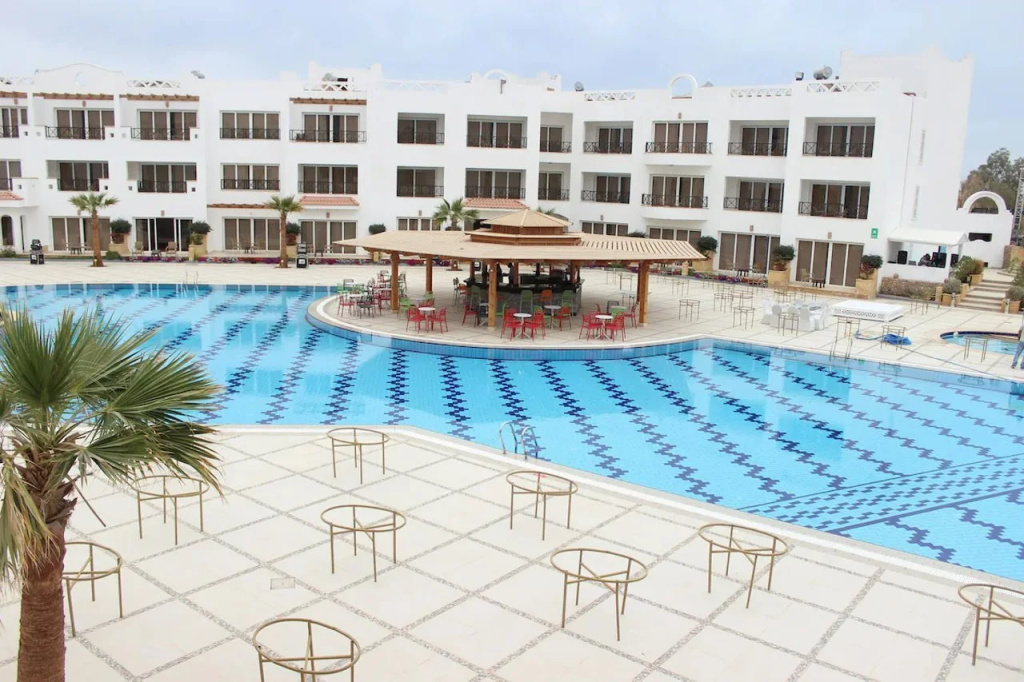 Old Vic Sharm Resort: A spacious outdoor pool bordered by a tiled deck, with a covered pavilion and outdoor seating.