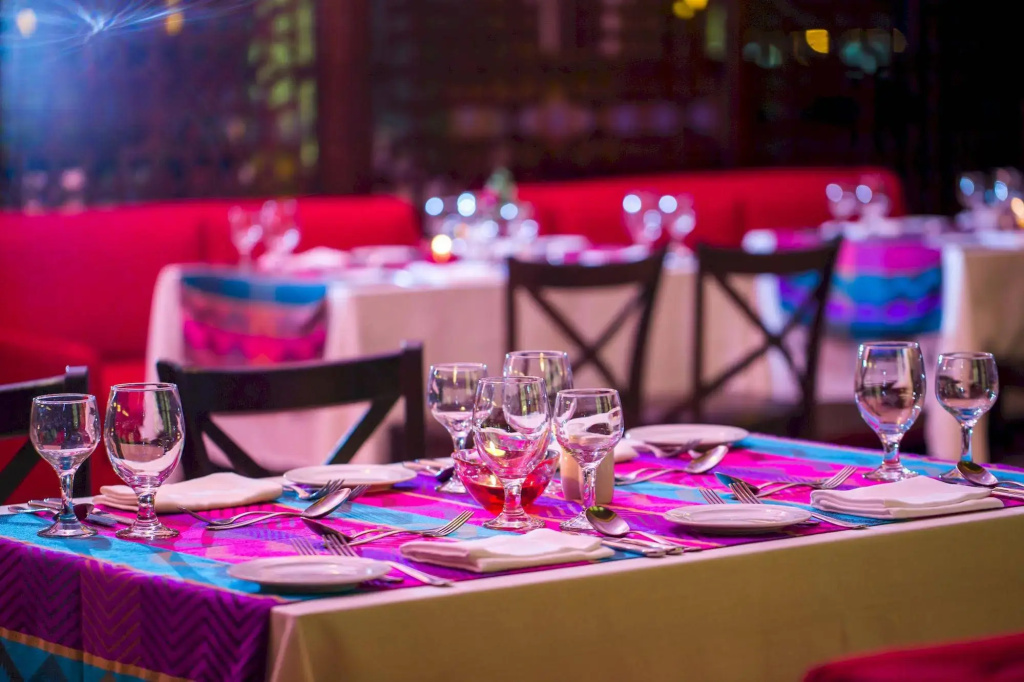 Jasmine Palace Resort & Spa: Colorful dining room with neatly set tables, glassware, and red banquette seating.