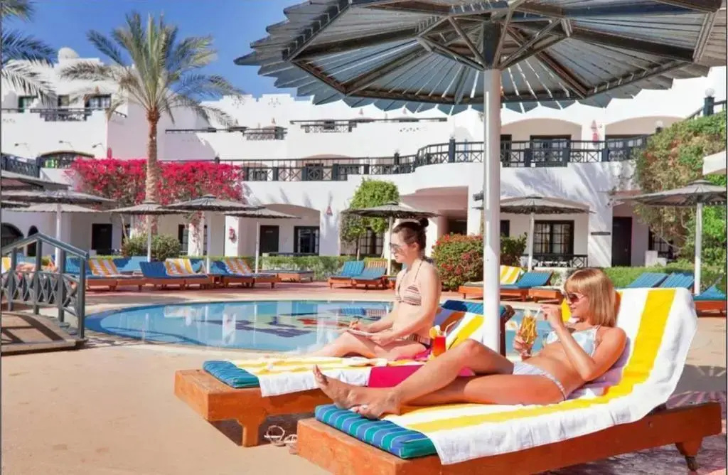 صورة: Verginia Sharm Resort & Aqua Park: Relax by the outdoor pool on a sun lounger in a landscaped resort setting.