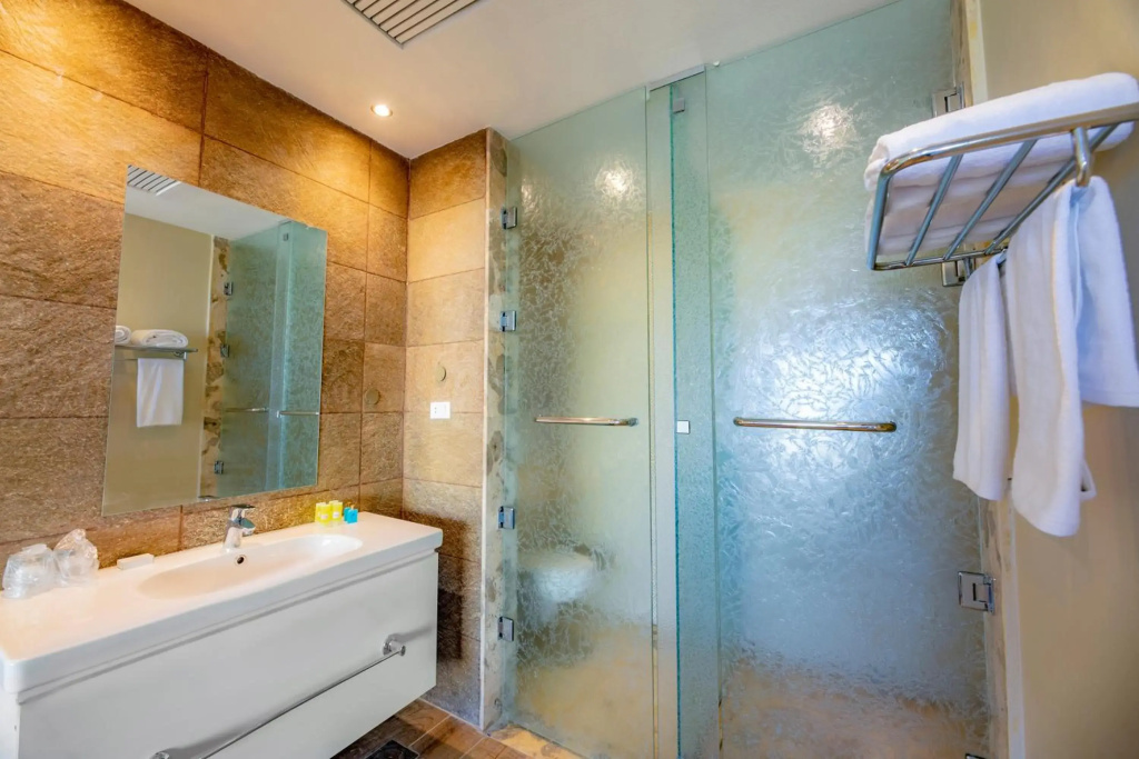 AJIRA Resort Sahl Hasheesh: Bathroom with a vanity sink, mirrored cabinet, and glass-enclosed shower with grab bars.