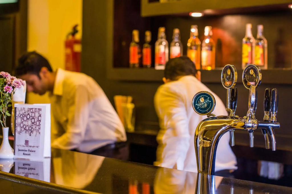 Jasmine Palace Resort & Spa: A warmly lit bar with beer taps, bottle displays, and staff serving behind the counter.