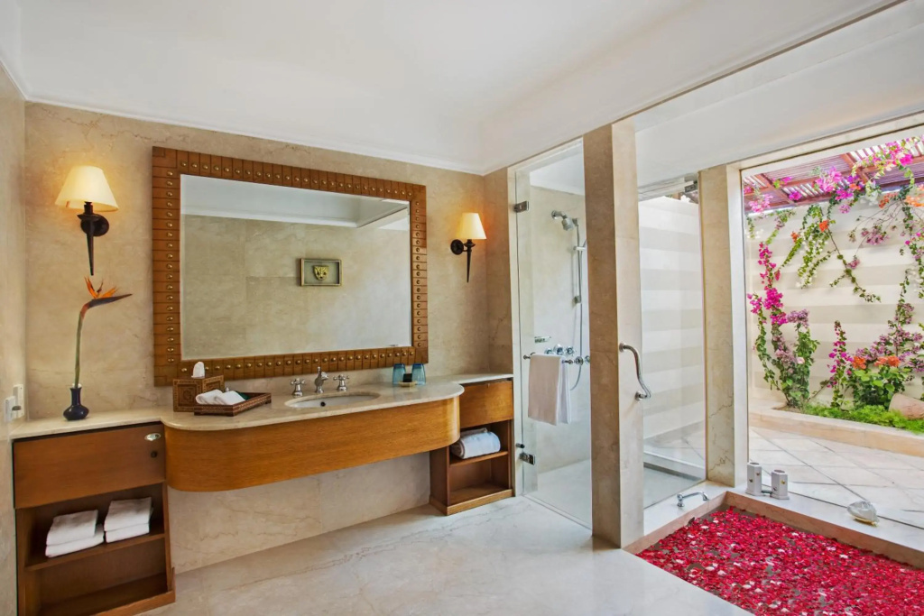 صورة: The Oberoi Beach Resort, Sahl Hasheesh: A spacious bathroom with a wood vanity, glass-enclosed shower, and views of a flowering garden.