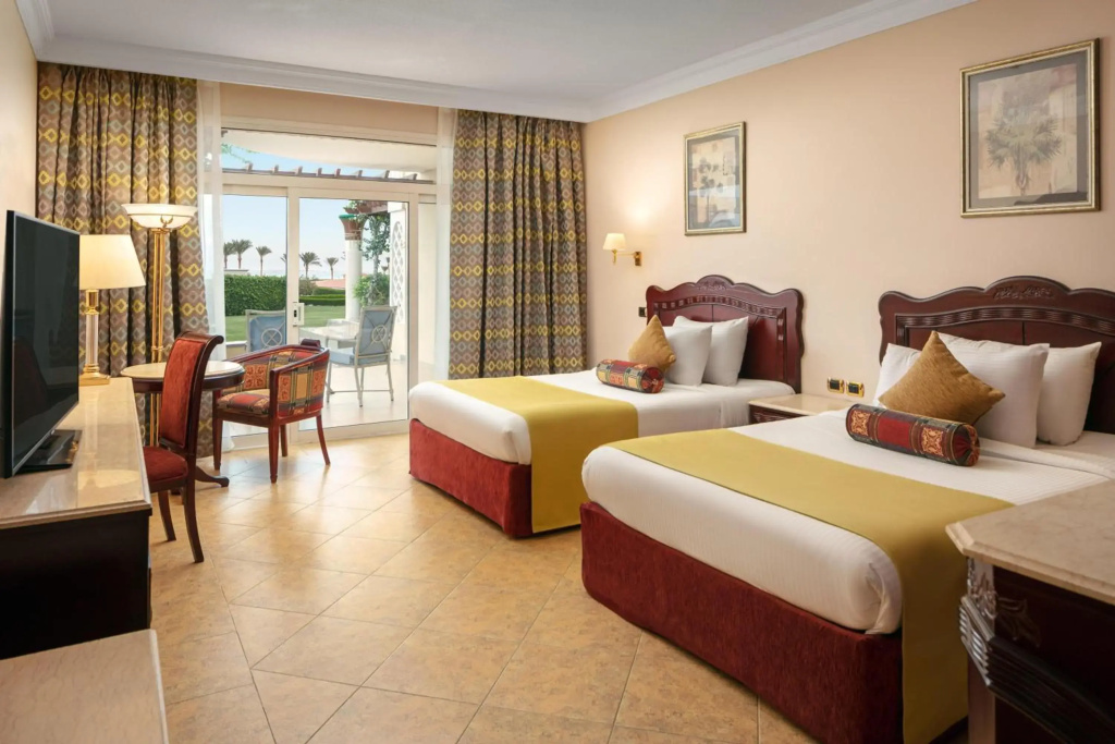 Palm Royale Resort - Soma Bay: Twin bedroom with a television and sliding doors opening to a furnished outdoor patio.