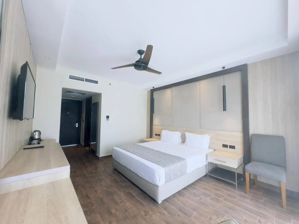 Panorama Naama Heights Sharm El Sheikh: Bright, modern guest room with a double bed, wall-mounted TV, ceiling fan, and seating.