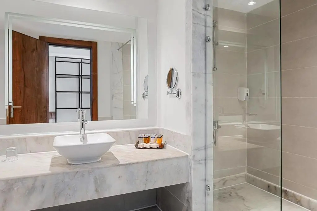 Albatros Makadi Resort: A bright bathroom with a marble-look vanity and a glass-enclosed shower.