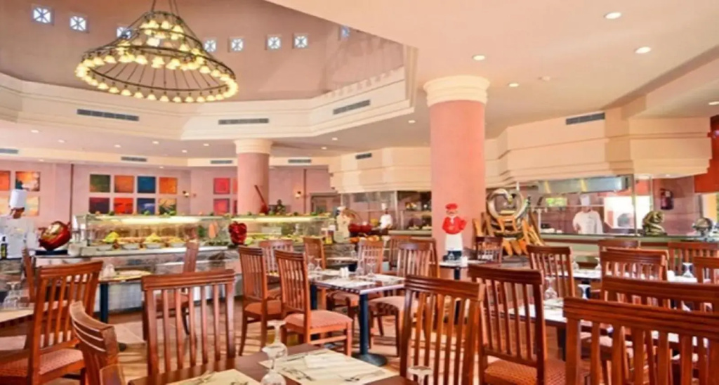 Charmillion Gardens Aquapark: A spacious indoor dining room with wooden chairs, tables, and a buffet counter.