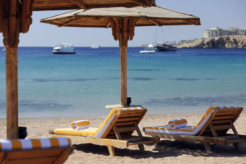 صورة: Naama Bay Promenade Beach Resort by Accor: Relax on cushioned sun loungers beneath wooden shade structures beside the clear blue sea.