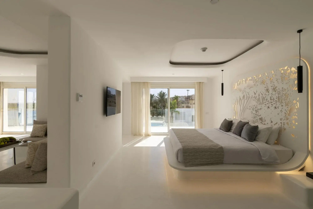 Meraki Resort Sharm El Sheikh: Bright modern bedroom with a lounge area and a pool visible beyond the sliding doors.
