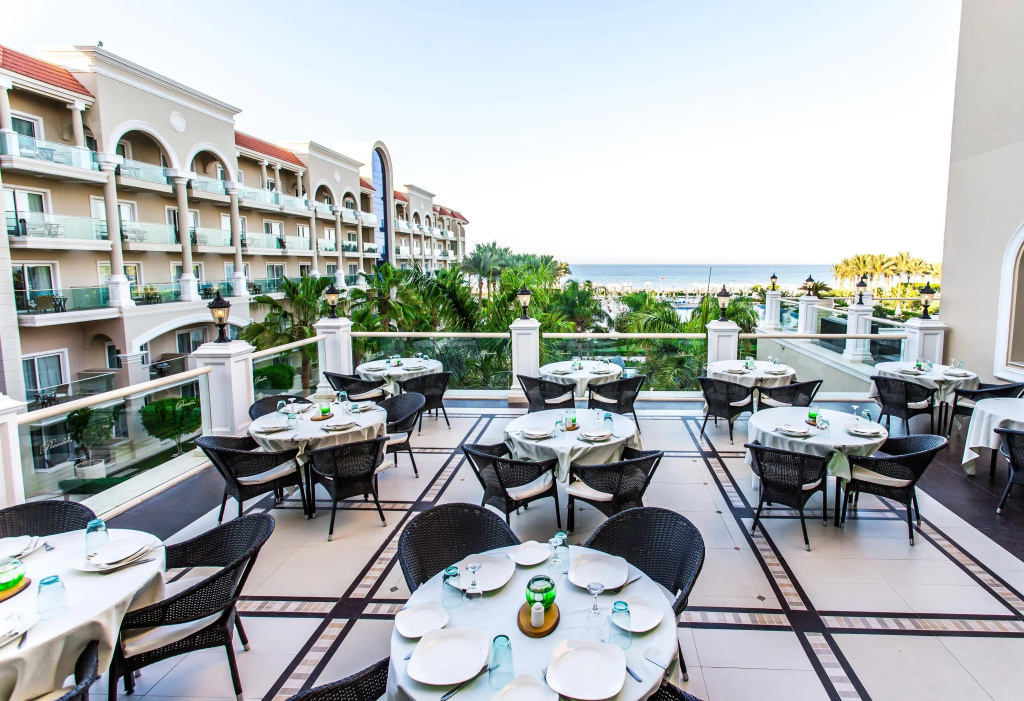 صورة: Premier Le Reve Hotel & Spa Sahl Hashesh -Adults Only: Outdoor dining terrace with set tables, woven chairs, and views toward the sea.