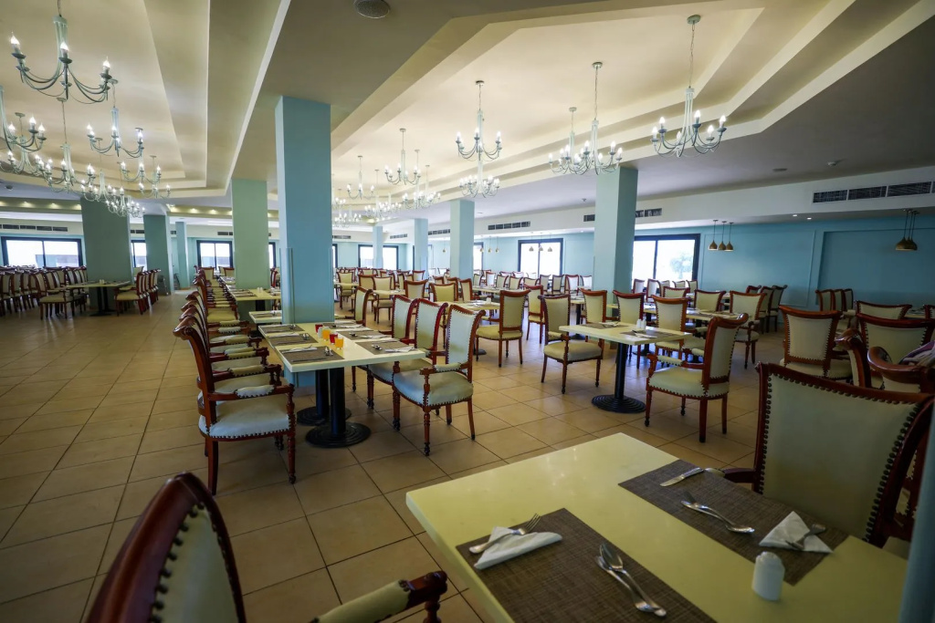 Blend Club Aqua Resort: A spacious dining room with neatly set tables, upholstered chairs, and chandeliers.